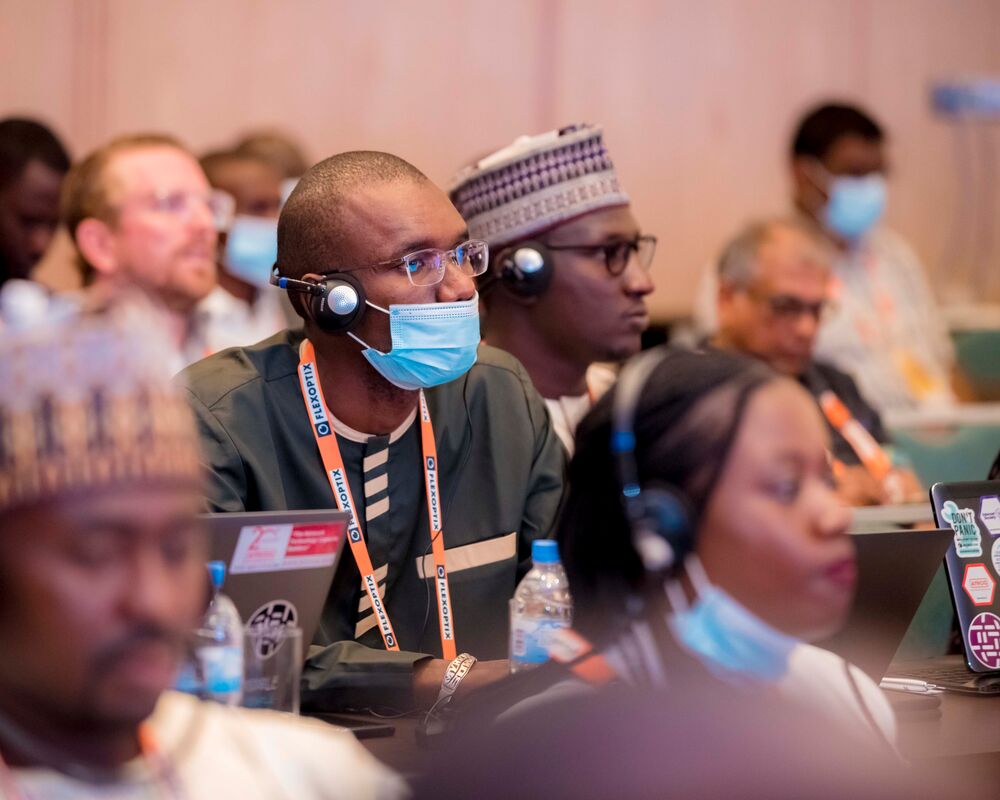 people sitting and listening, one wearing a mask an headphones