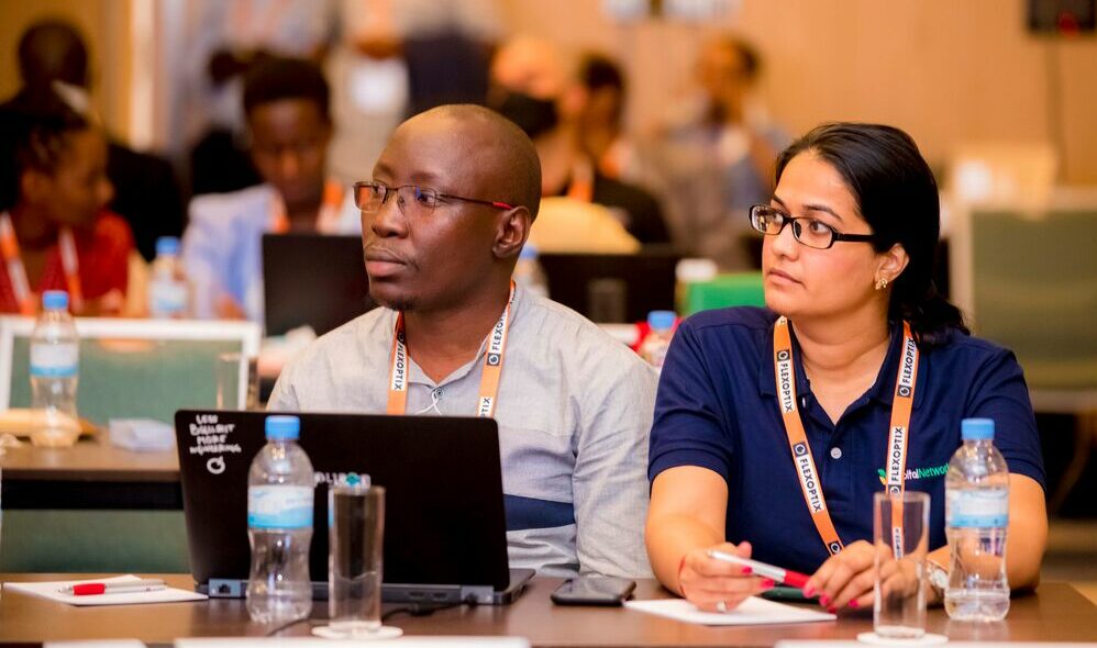 a man and a woman listening to a speaker in a conference room