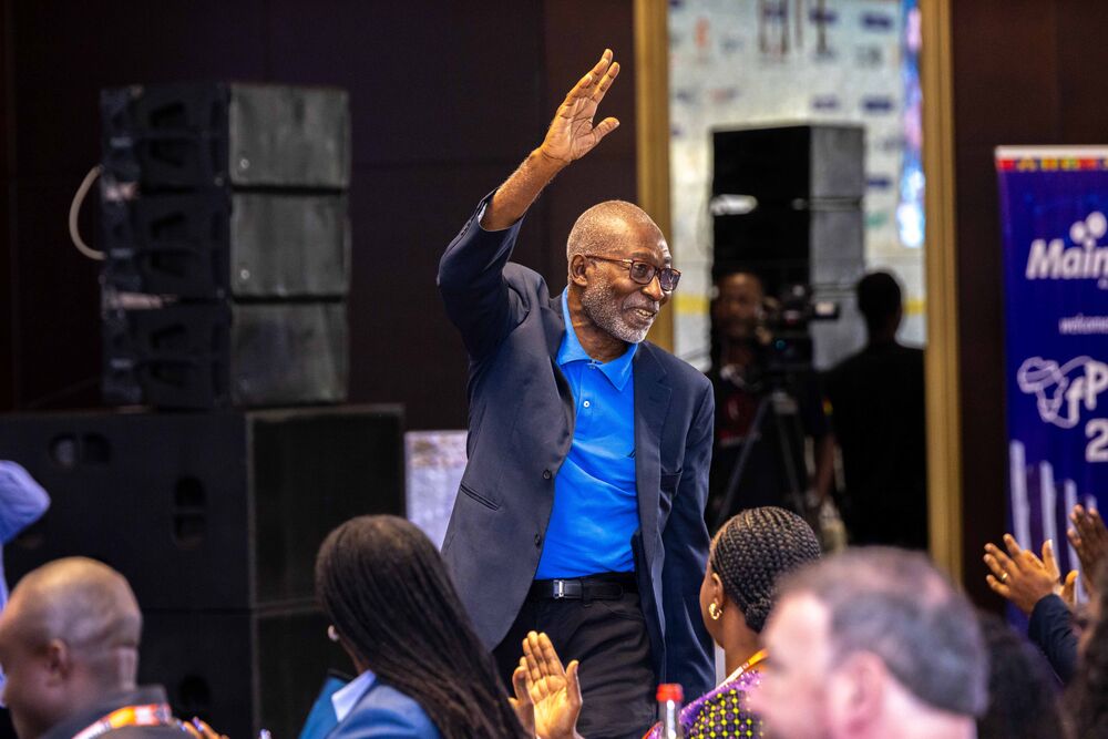 a man with glasses waving at a crowd