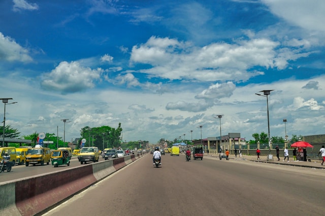 A bustling road with cars and pedestrians.